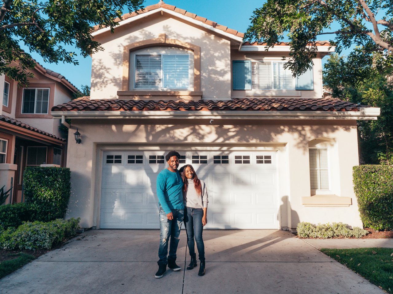 A happy couple standing together outside their newly purchased house